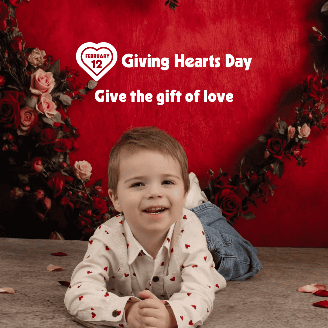happy little boy lying on his stomach in front of this message: February 12 • Giving Hearts Day • Give the gift of love.
